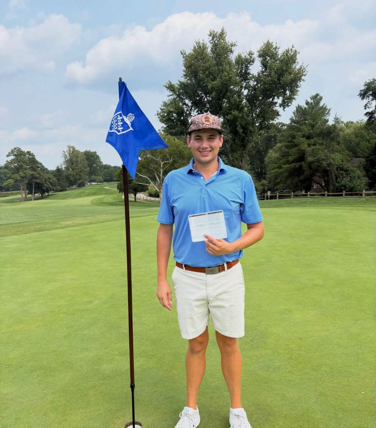 Ashton Harper on the green at Roanoke Country Club holding the scorecard from his course-record 59