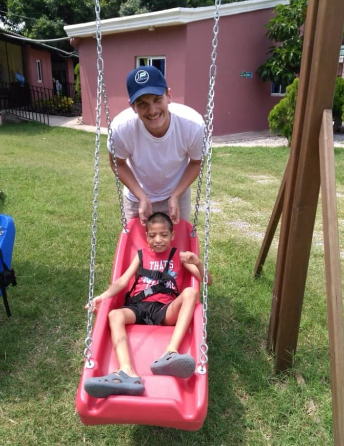James Kasza pushing a young boy on an adaptive swing in Guatemala